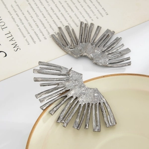 Close-up of irregular fan-shaped silver stud earrings with textured metallic finish