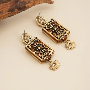 Détail de boucles d'oreilles rétro dorées avec motifs floraux creux et résine ambre