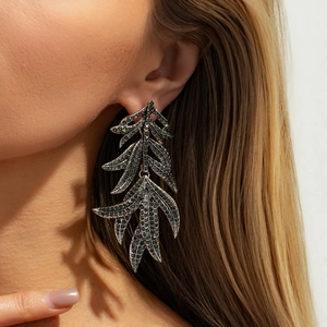 Détail des boucles d'oreilles feuilles à étages avec strass gris foncé sur modèle