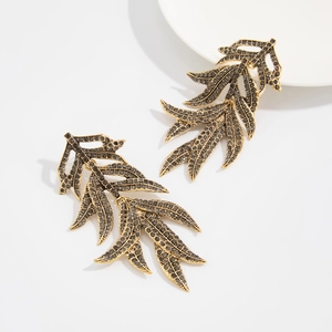 Detailed close-up of gold leaf drop earrings featuring dark grey micro-pave crystals