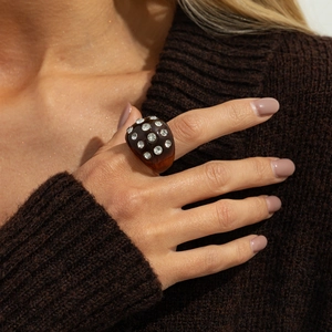 Detail of dark brown resin ring with embedded sparkling crystals on knit fabric