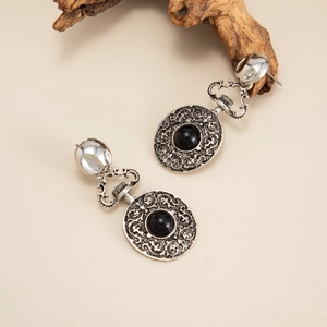 Dettaglio ravvicinato di orecchini vintage in argento con pietre nere e motivi traforati