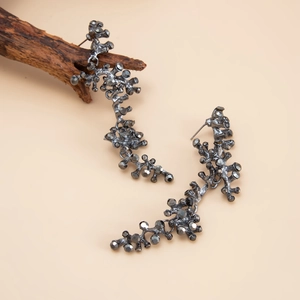 Detailed view of gunmetal branch earrings with dark crystals on a wood decor