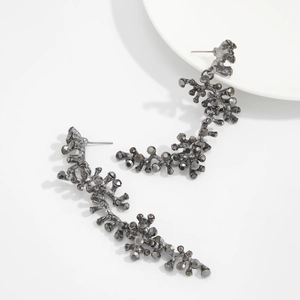 Detailed view of gunmetal branch earrings with dark crystals on a white plate
