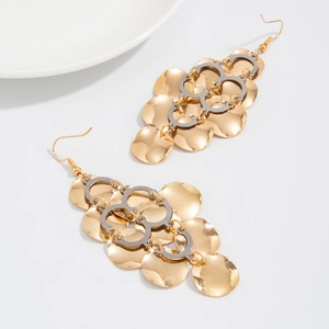Detailed view of long gold drop earrings with polished geometric sequins and silver loops