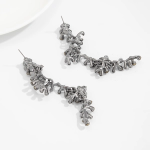 Detailed view of silver organic branch-shaped drop earrings with a vintage coral texture