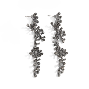 Vue détaillée des boucles d'oreilles branche en métal avec cristaux gris foncés