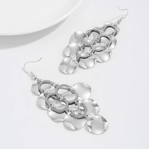 Detailed macro view of silver geometric sequin tassels on long interlocking dangle earrings