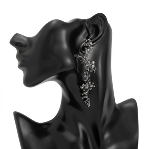 Vue détaillée de longues boucles d'oreilles en branche avec des strass sombres brillants