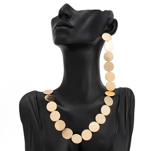 Detailed macro view of gold brushed metal disks on geometric necklace and drop earrings