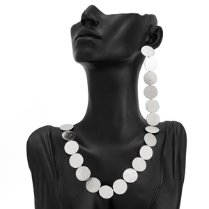 Detail of silver brushed metal geometric disc necklace and long tassel earrings on black bust