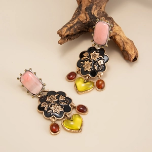 Dettaglio di orecchini vintage con pietre rosa e ciondoli a forma di cuore pendenti