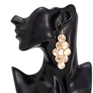 Close-up of golden metallic circular discs layered in a waterfall dangle earring style