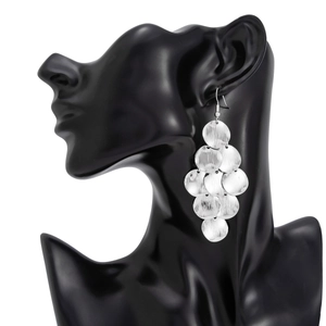 Detail of layered silver metal disk earrings with brushed texture on a model neck