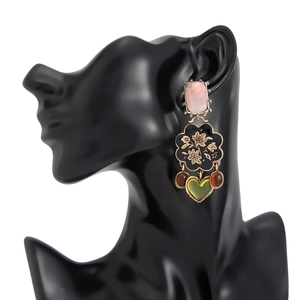Détail de boucles d'oreilles vintage avec pierres roses et breloques émaillées
