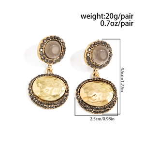 Détail de boucles d'oreilles pendantes ovales vintage avec texture métal et strass