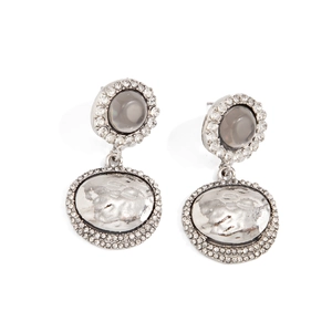 Détail de boucles d'oreilles argentées avec pierre grise, strass et ovale à effet martelé