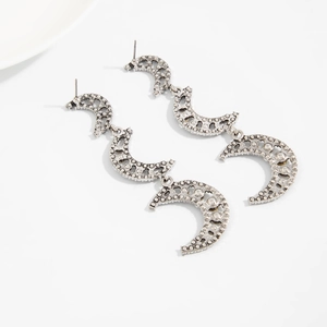 Close-up of silver triple crescent moon drop earrings with textured alloy finish