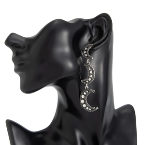 Détail de boucles d'oreilles pendantes avec trois lunes croissantes et strass pavés