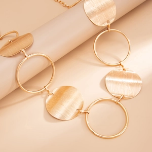 Detail of a gold metal chain waist belt featuring hollow rings and brushed textured disks