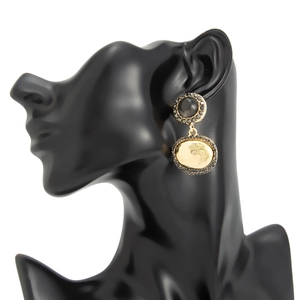 Détail des boucles d'oreilles vintage avec pierre noire et métal doré à effet martelé