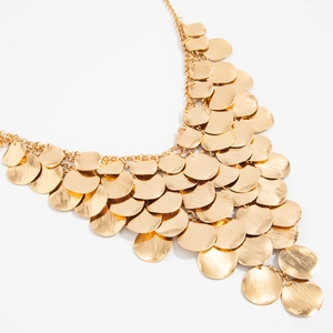 Detailed macro shot of layered golden metal discs with brushed texture on Y-shaped necklace