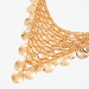 Detail of layered gold fringe necklace featuring polished flat round metallic discs and chains