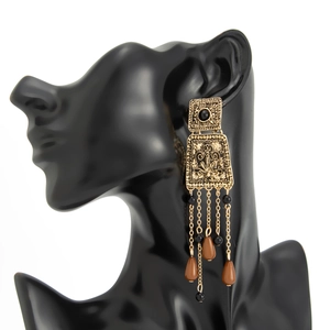 Vue détaillée des boucles d'oreilles vintage dorées avec carrés évidés et longs glands