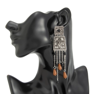 Détail de boucles d'oreilles vintage avec glands argentés et perles rouges sombres