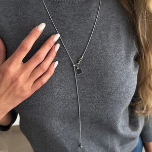Detail van zilveren Y-vormige slangenketting met minimalistische zwarte vierkante hanger