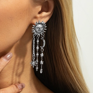 Détail de boucles d'oreilles vintage argentées aux motifs célestes soleil lune étoile