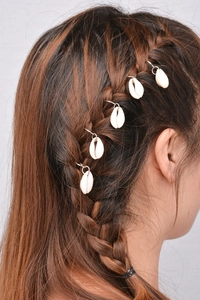 Close-up of bohemian cowrie shell hair rings attached to a braided hairstyle