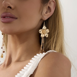 Detailansicht goldener Blumenohrringe mit Quasten und Bernsteinperlen am Model