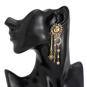 Détail de boucles d'oreilles pendantes dorées vintage avec breloques soleil, lune et étoile