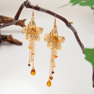 Goldene Blumenohrringe mit langen Bernsteinperlen-Quasten an einem Ast hängend