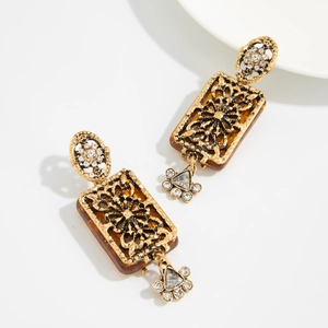 Détail de boucles d'oreilles vintage en or avec résine ambre, motif fleuri et cristaux
