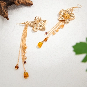 Detailaufnahme goldener Blumen-Ohrringe mit bernsteinfarbenen Perlen und Champagner-Kristallen