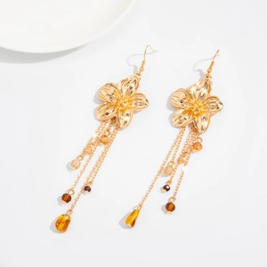 Detailansicht goldener Blumen-Ohrringe mit Quasten und Bernsteinperlen auf Weiß