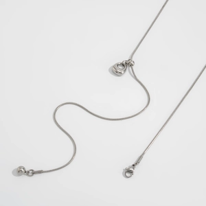 Detail van verstelbare zilveren slangenketting met een schuivende hartvormige hanger