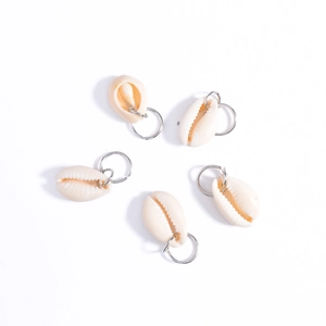 Detail of five natural white cowrie shell charms with silver rings for braids and locs
