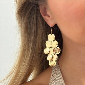 Macro shot of gold layered disc tassel earrings with brushed metal texture details
