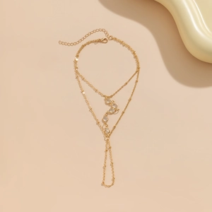 Dettaglio di un bracciale anello bohémien dorato con doppie catene e pietre zirconi