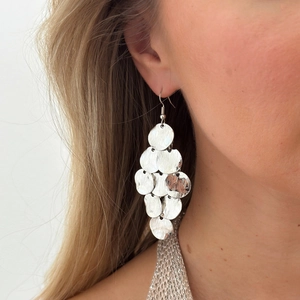 Close-up of silver tiered circular sequin fringe earrings on model with brushed texture