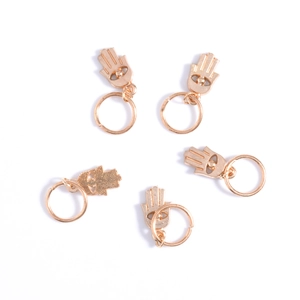 Close-up of five golden Hamsa Hand charms on hair rings for braids and dreadlocks