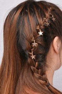Detailed view of golden star charm hair rings woven into a braided hairstyle for women
