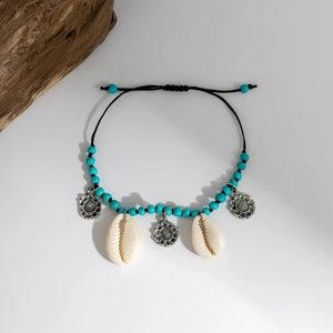 Dettaglio di una cavigliera boho con conchiglie naturali e perline turchesi su cordino