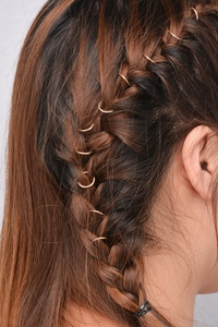 Detail view of rose gold alloy hair rings styled on creative bohemian braid hairstyles