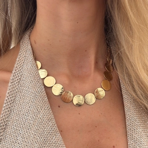Detail of gold geometric round disc necklace with brushed finish on a model