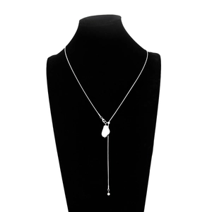 Detail van zilveren Y-vormige lange ketting met witte hanger op een zwarte bustehouder