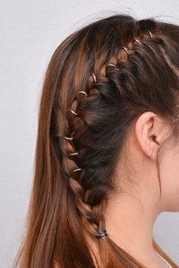 Close-up of silver minimalist hair rings woven into a side braid hairstyle